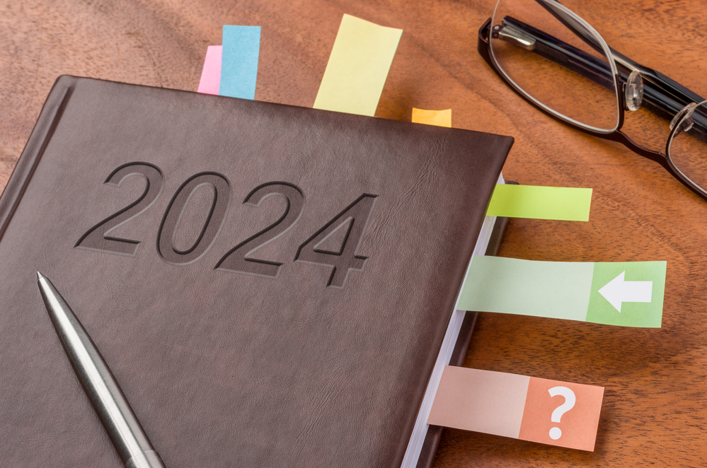 Brown notebook with 2024 on cover, marked with tabs and sitting on desk